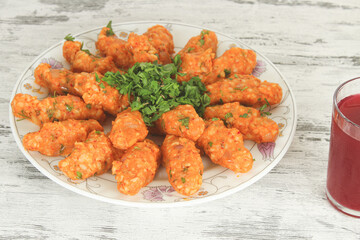 Potato dumplings in white plate with cold red drink on table. Sitting view. Vegan and healthy food concept idea. Potato dumpling known as 'patatesli bulgur kofte' in Hatay, Turkiye.