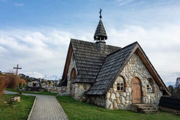 Entrance to small stone chapel with a cross on a roof in Murzasichle graveyard in Poland in High Tatras