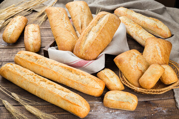 Assortment of different types of bread, baguettes on rustic wooden background