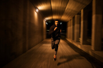 Young man running and exercising in a tunnel in the city