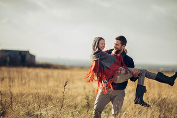 Young man carrying his girlfriend on a field in the countryside