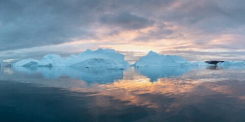 Iceberg at sunset. Nature and landscapes of Greenland. Disko bay. West Greenland. Summer Midnight Sun and icebergs. Big blue ice in icefjord. Affected by climate change and global warming concept.