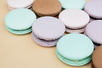 Different pastel colors pastry macarons on a beige background