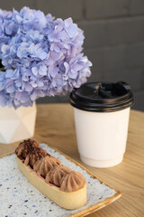 Cake with shortcrust pastry and cream on a wooden cafe table on a background of flowers