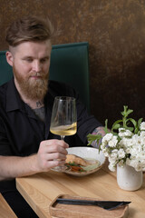 Wine in a glass in a man's hand at a restaurant table