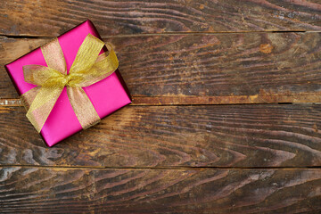 pink gift box with golden ribbon on wood table. flat lay