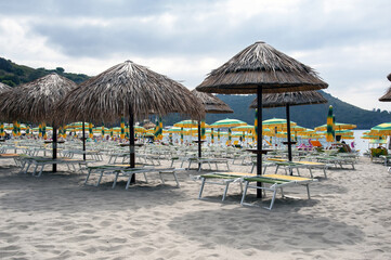Lido with parasols and sunbeds on the sandy beach in the bay. Marina di Camerota, Salerno, Italy.