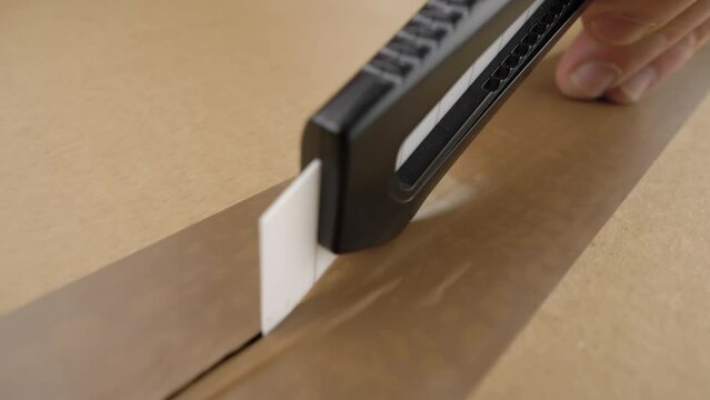 Closeup hand opening parcel box with clerical knife