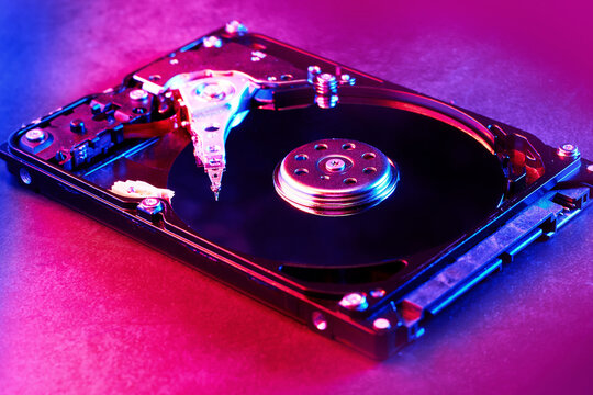 Disassembled hard drive from the computer, hdd in red-blue light. Opened hard drive from the computer hdd with mirror effects Part of computer pc, laptop Closeup HDD