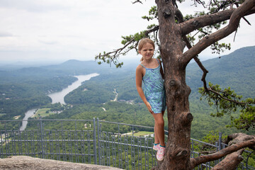 Girl in tree on side of mountain with lake view background