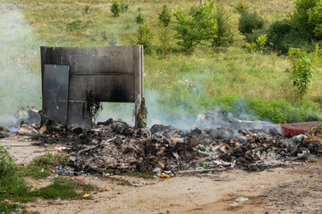 A pile of garbage burns and smokes. Pollution of the environment with household waste