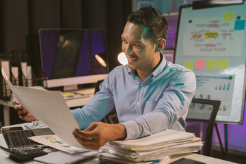 Fototapeta premium Young Asian businessman talking on the phone late night hustle ambitious Working overtime talking on the phone in the organization