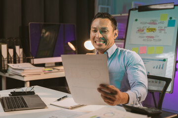 Fototapeta premium Young Asian businessman talking on the phone late night hustle ambitious Working overtime talking on the phone in the organization