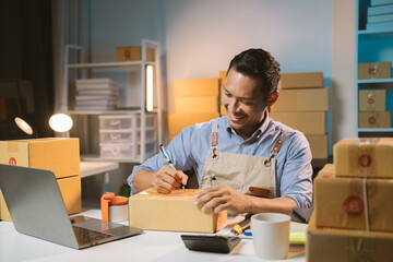 Asian male small business owner using mobile app on smartphone checking parcel box. Warehouse...