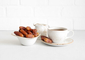 Tea and dried dates in a bowl on white background. Turkish sweets. Natural healthy food.