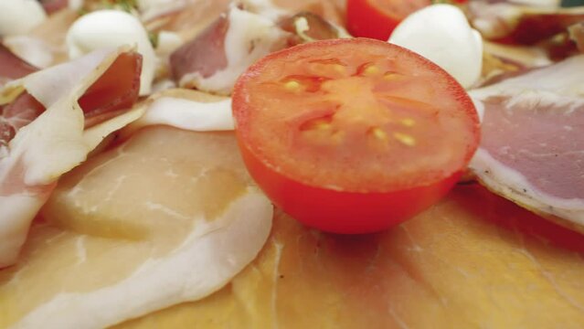 Slices of pork dried ham, prosciutto crudo. Close up of raw jamon with with mozzarella and tomatoes