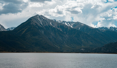 mountains with cloudy sky next to a lake