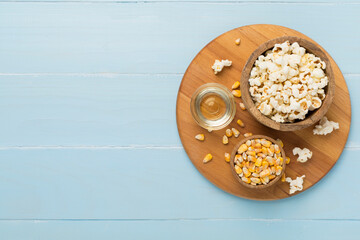 Prepared popcorn with ingredients on wooden background, top view