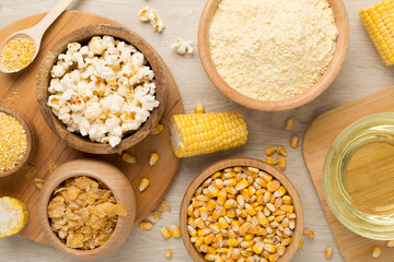 Maize products with fresh corn cobs on wooden background, top view
