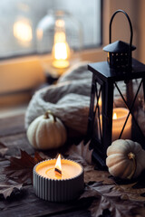 Cozy autumn composition with aromatic candle, pumpkins, wool sweater, leaves, cinnamon....