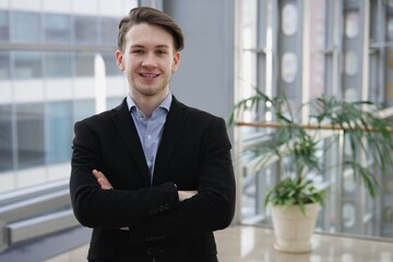 Portrait of young businessman, office worker or college or university student in shirt and jacket, suit looking at camera indoors 