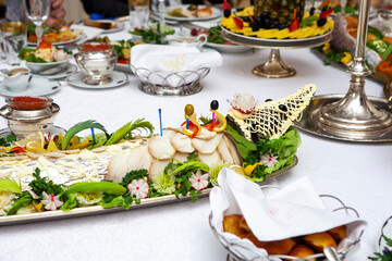 Russian-style table, dishes with caviar, cold cuts, fruits, vegetables, stuffed fish in the form of...