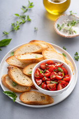 Making tomato basil bruschetta with toasted baguette and herbs
