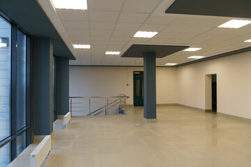 A spacious empty room with columns and no furniture. The concept of a comfortable office. The interior space of a modern office building. Bright and clean interior design of a luxurious living room.