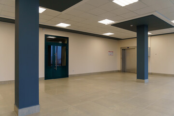 A spacious empty room with columns and no furniture. The concept of a comfortable office. The interior space of a modern office building. Bright and clean interior design of a luxurious living room.