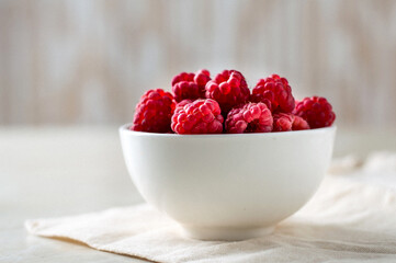 Bowl with raspberries on the kitchen table, light background, close, macro..