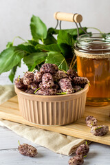 A bowl of white mulberry and a jar of mulberry jam are on a board in the kitchen..