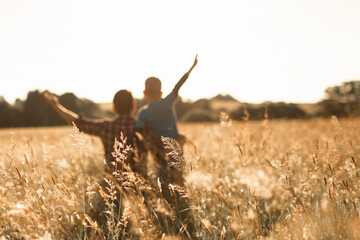 Happy joyful father and son in a field watching the sunset enjoying time together bonding in nature	