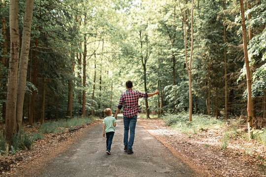 Father and son spending time outdoors enjoying a nature walk hike in the forest	