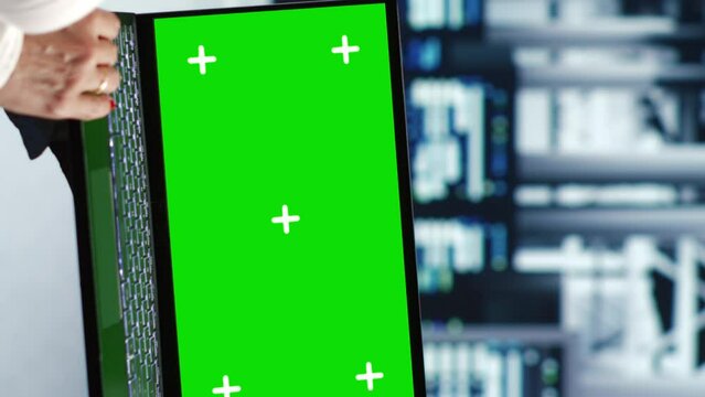 Vertical video Aged technician in servers center housing high end processors capable of quickly and efficiently performing complex computations and data analysis, using mockup laptop to mend glitches