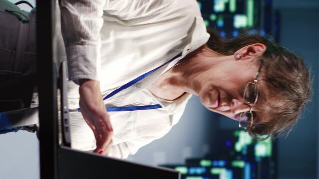 Vertical video Focused repairman in cloud computing company headquarters housing high end servers capable of efficiently performing complex computations and data analysis, using tablet to nullify
