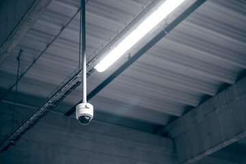 Digital surveillance camera on the ceiling in a warehouse room - obrazy, fototapety, plakaty