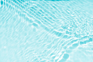 Blue water with ripples on the surface. Defocus blurred transparent blue colored clear calm water surface texture with splashes and bubbles. Water waves with shining pattern texture background.
