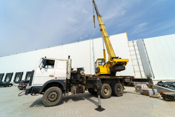 Crane truck against the background of a large warehouse