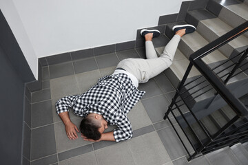 Unconscious man lying on floor after falling down stairs indoors, above view © New Africa