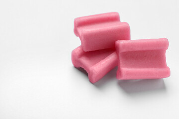 Tasty pink chewing gums on white background, closeup. Space for text