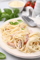 Plate of tasty pasta Carbonara with basil leaves on table, closeup