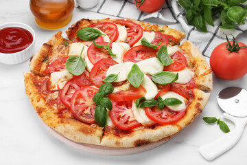 Delicious Caprese pizza with tomatoes, mozzarella and basil served on white marble table, closeup