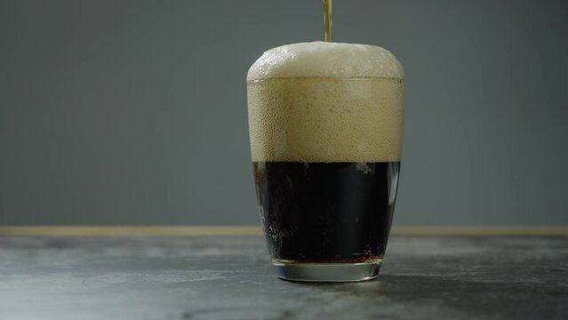 A glass with being filled with carbonated soft drink, you can see the fresh bubbles of the beverage. Brown Soda pouring to a glass. Pouring Soda. Slow motion B roll 4k.
