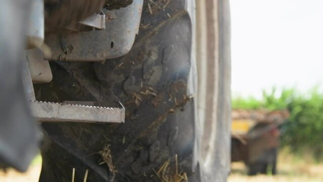 HD, low angle, close-up shot of giant tractor wheels rolling through the mud on an agricultural farm. This realistic footage captures the power and movement of heavy farming machinery in action, provi