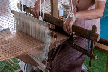 The traditional weaving of handmade cotton on the manual wood loom in Thailand.