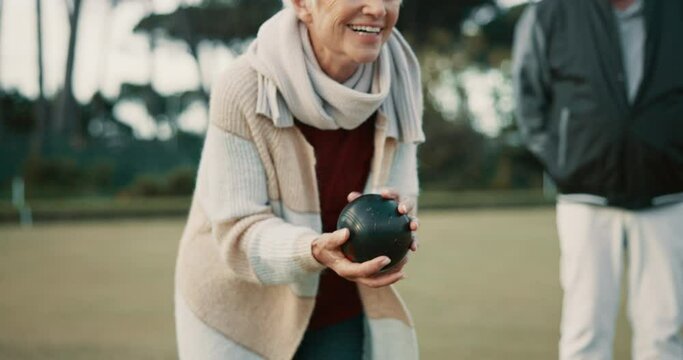 Senior woman, bowling and park on grass for sport, fitness and games for competition, health or fun. Elderly people, metal ball and lawn for contest, funny laugh or workout with blowing for good luck
