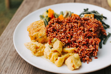 Delicious lunch with rice, vegetables and curry on a white plate close-up