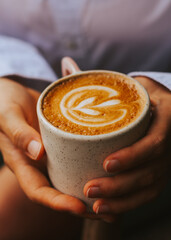 Women's hands hold delicious specialty coffee of excellent quality. Hot cappuccino at brunch in a cafe