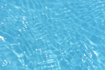Blue water with ripples on the surface. Defocus blurred transparent blue colored clear calm water surface texture with splashes and bubbles. Water waves with shining pattern texture background.