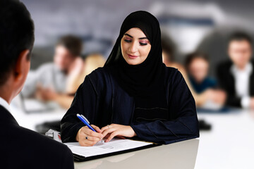 Emarat bank teller or customer signing a contract inside a financial bank. Arab Emirati to sign a...